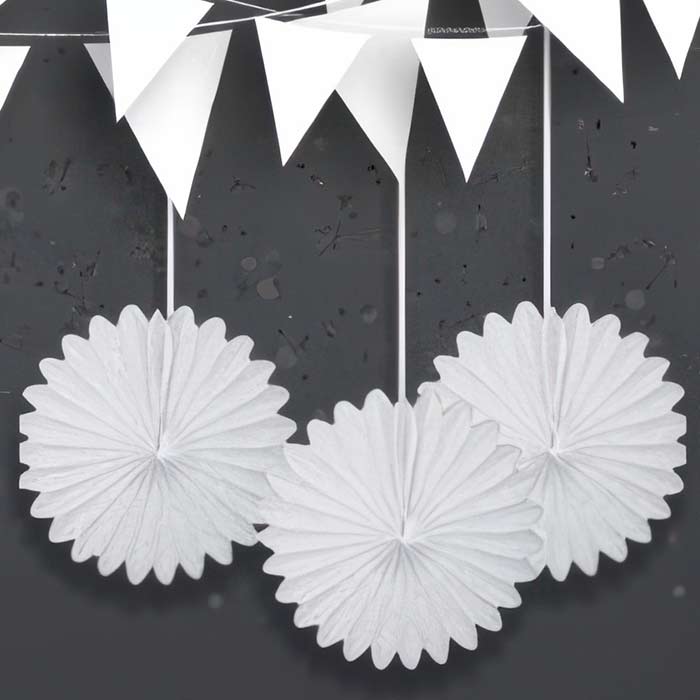 Elegant display of white party decorations featuring hanging white puff balls and bunting for a sophisticated look